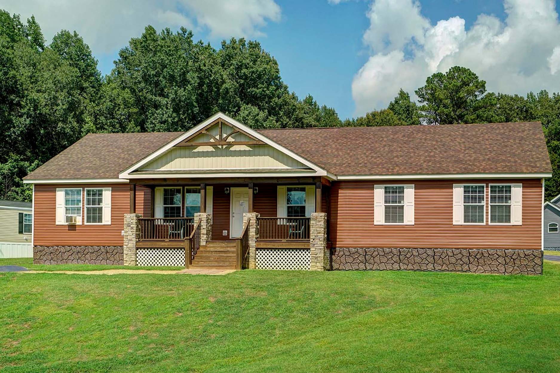 A one-story brown house with a front porch and a gabled roof.
